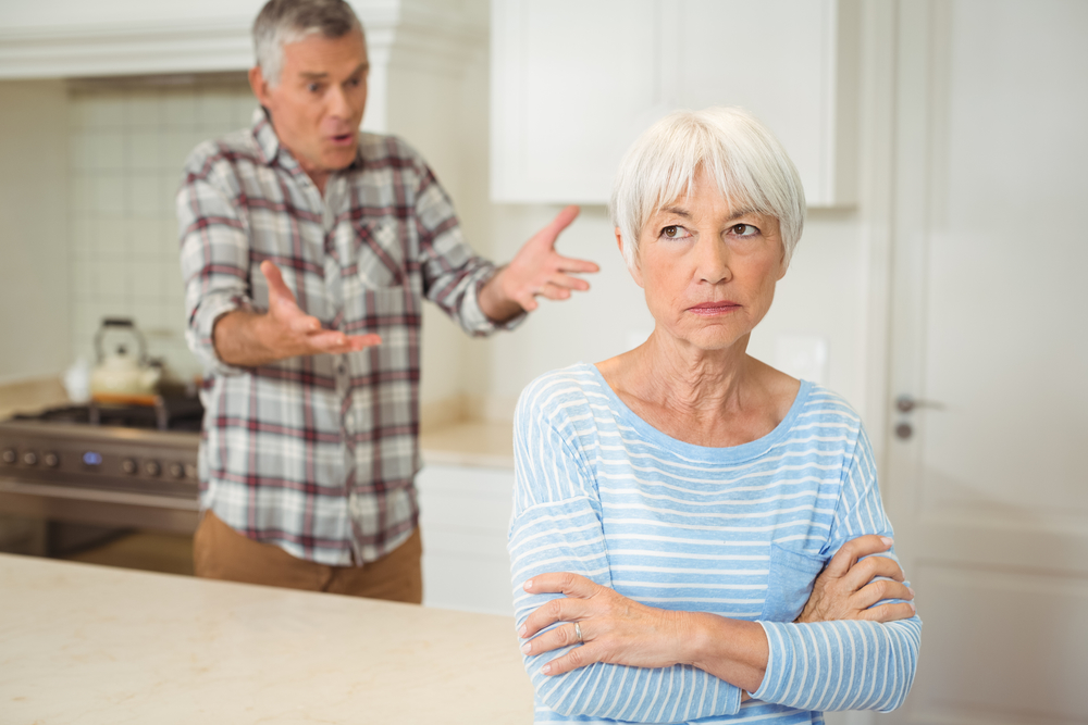 Older man and woman arguing in a white kitchen