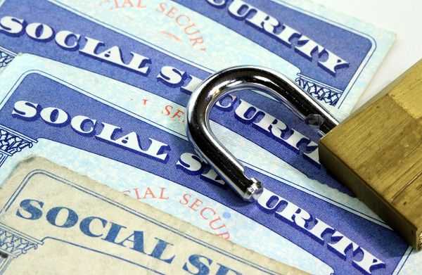 Overlapping social security cards with an open padlock on top.